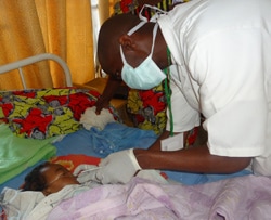 An influenza surveillance nurse collects a sample from a child with acute respiratory illness at a local hospital in Rwanda.