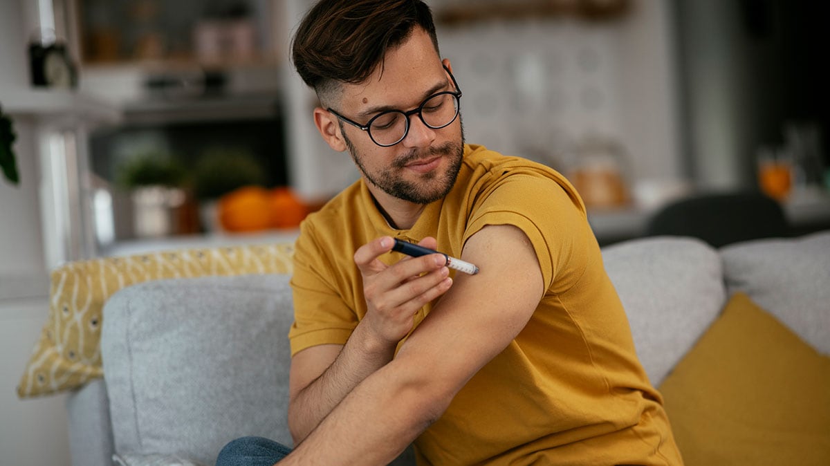man on couch using insulin pen