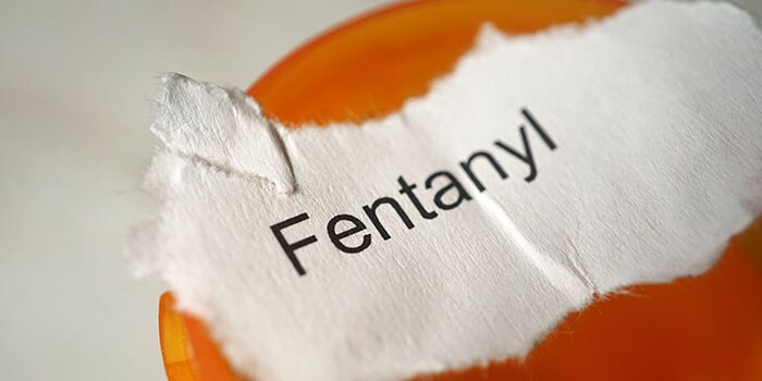 A pill bottle and a scrap of paper with the word Fentanyl on it