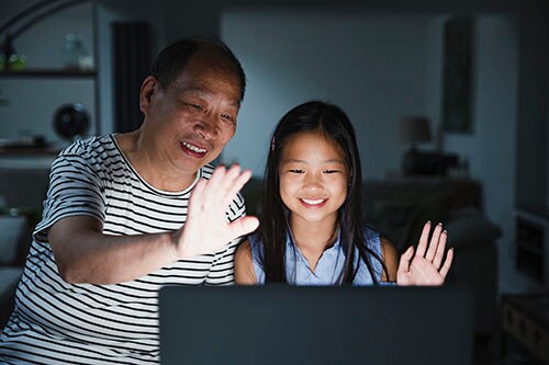 Child and older adult staying connected with family using a laptop