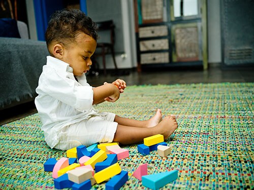 Toddler playing with blocks on carpet