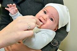 un bebé recién nacido en los brazos de su madre recibiendo la vacuna contra el rotavirus